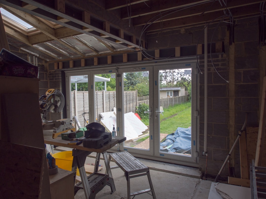 A person stands in front of their home, carefully taking notes on a clipboard while assessing storm damage to the siding and windows for an insurance claim.