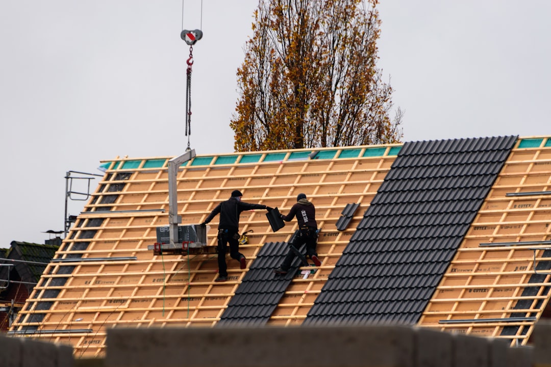 A skilled roofer in safety gear meticulously installing new shingles on a residential home, symbolizing expert installation and quality craftsmanship.
