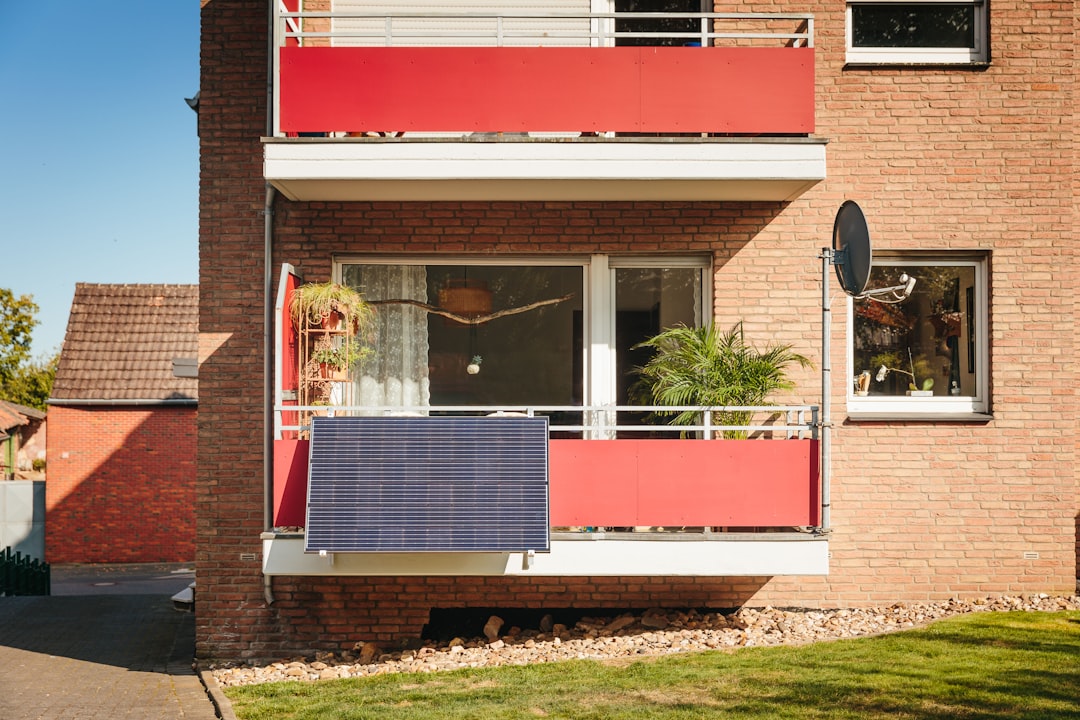 A homeowner stands in front of their modern house, using a tablet to research real estate information, symbolizing the shift to digital home selling.