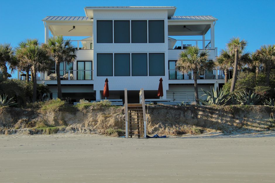 Beautiful, modern coastal home with excellent curb appeal and a green lawn, photographed on a bright, sunny day.